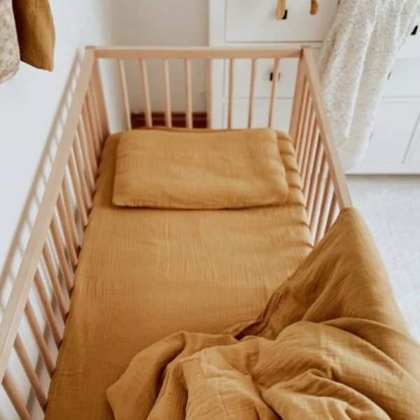 posteljina za bebe od muslina oker boje na krevecu