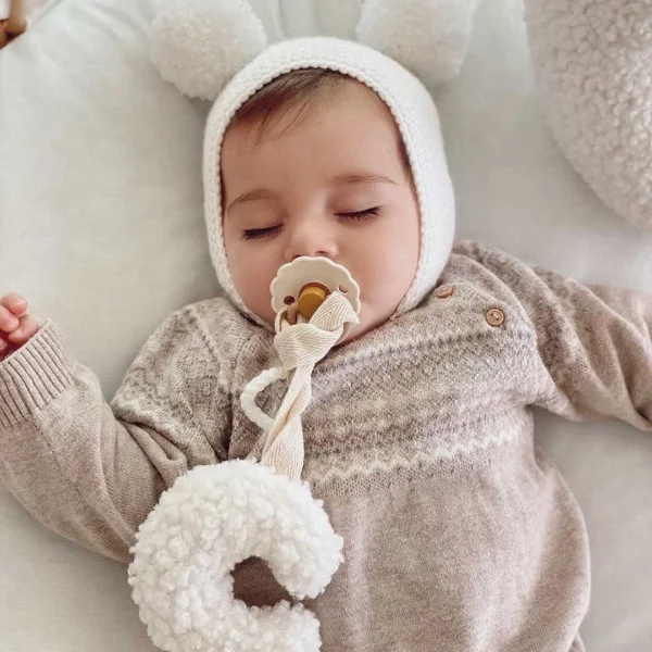 lancic za culu na vezivanje u obliku polumeseca bele boje od teddy materijala zavezana za cuclu u ustima bebe koja spava