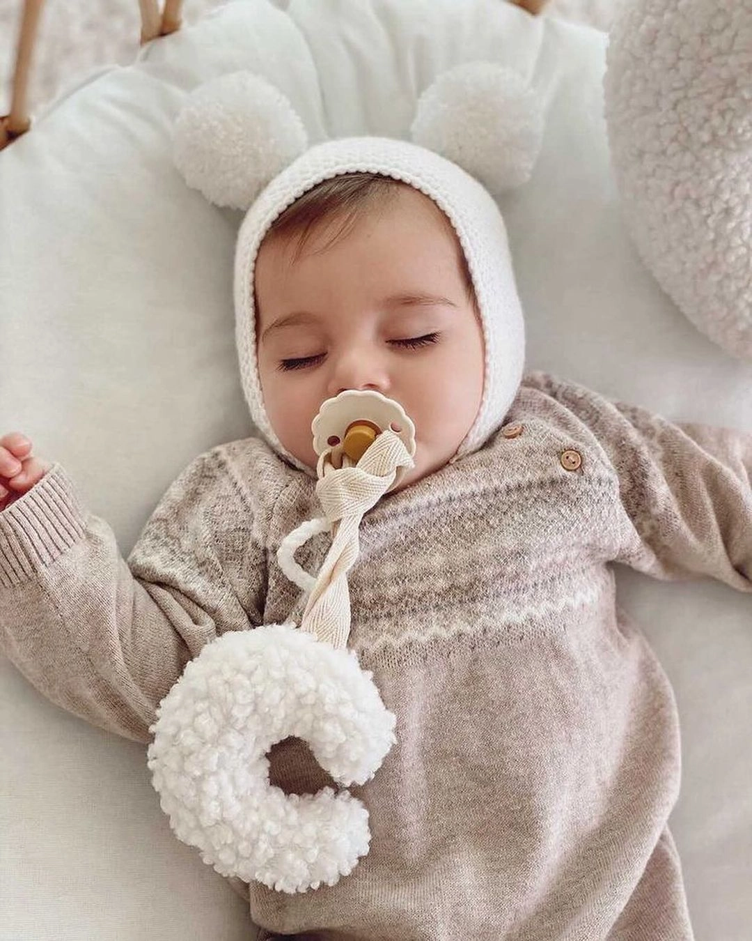 lancic za culu na vezivanje u obliku polumeseca bele boje od teddy materijala zavezana za cuclu u ustima bebe koja spava
