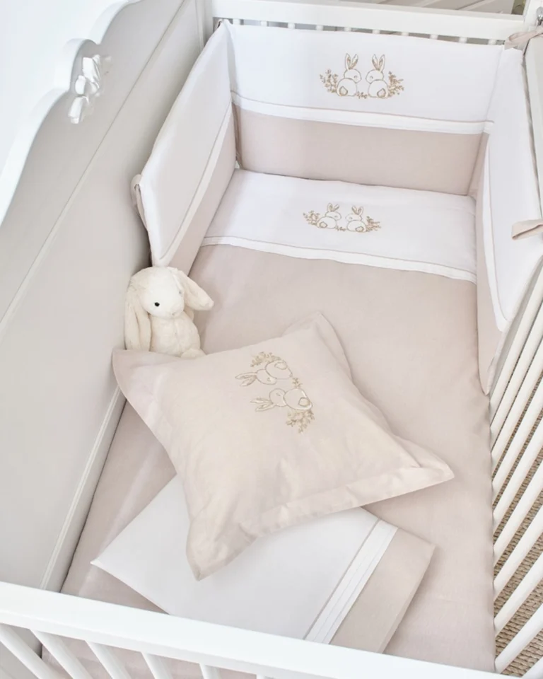 posteljina za bebe set od osam delova u kombinaciji bez i bele boje sa vezenim motivom zeca delovi prikazani na beloj pozadini