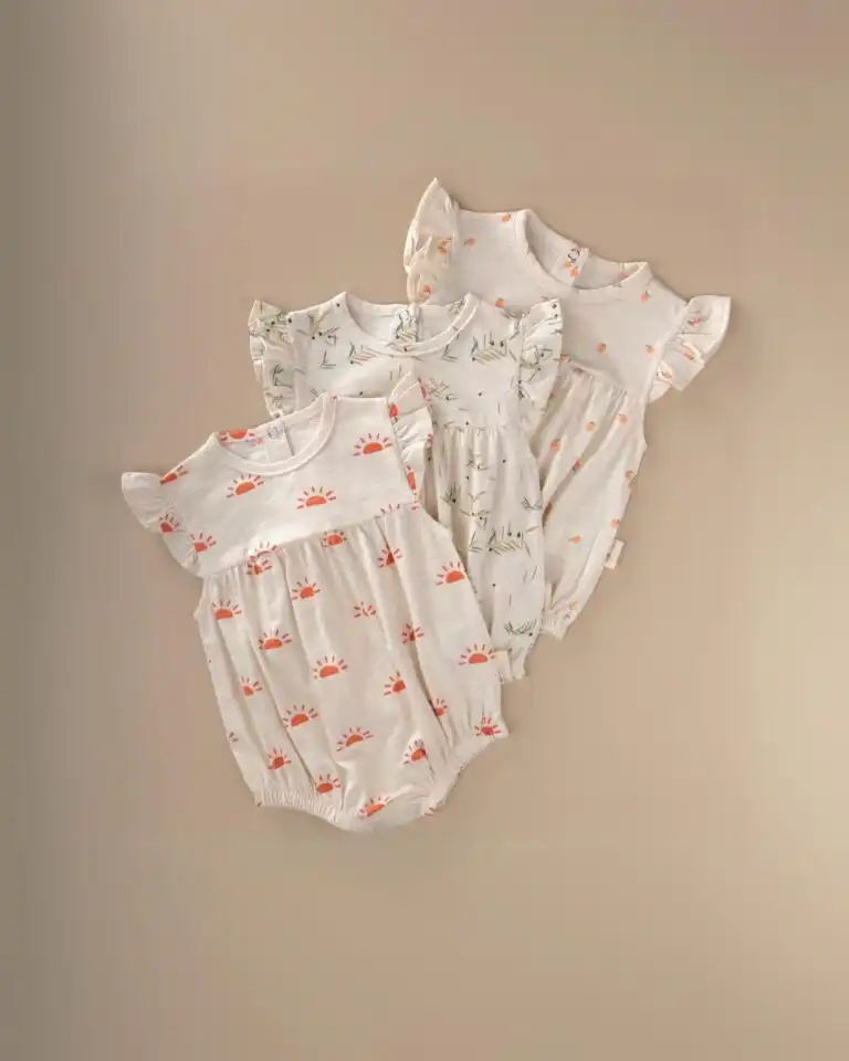 romper kratkih rukava sa risevim na rukavima krem boje sa dezenima sunca pomorandze i masline razlozeni jedan na drugi na bez pozadini