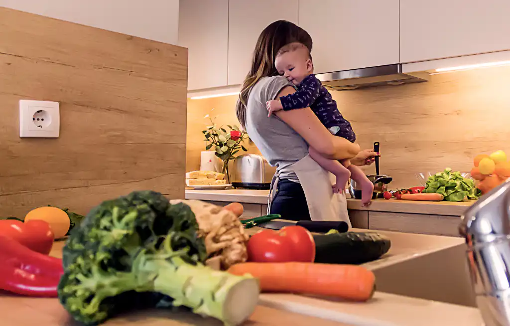 ishrana tokom dojenja mama nosi bebu u kuhinji