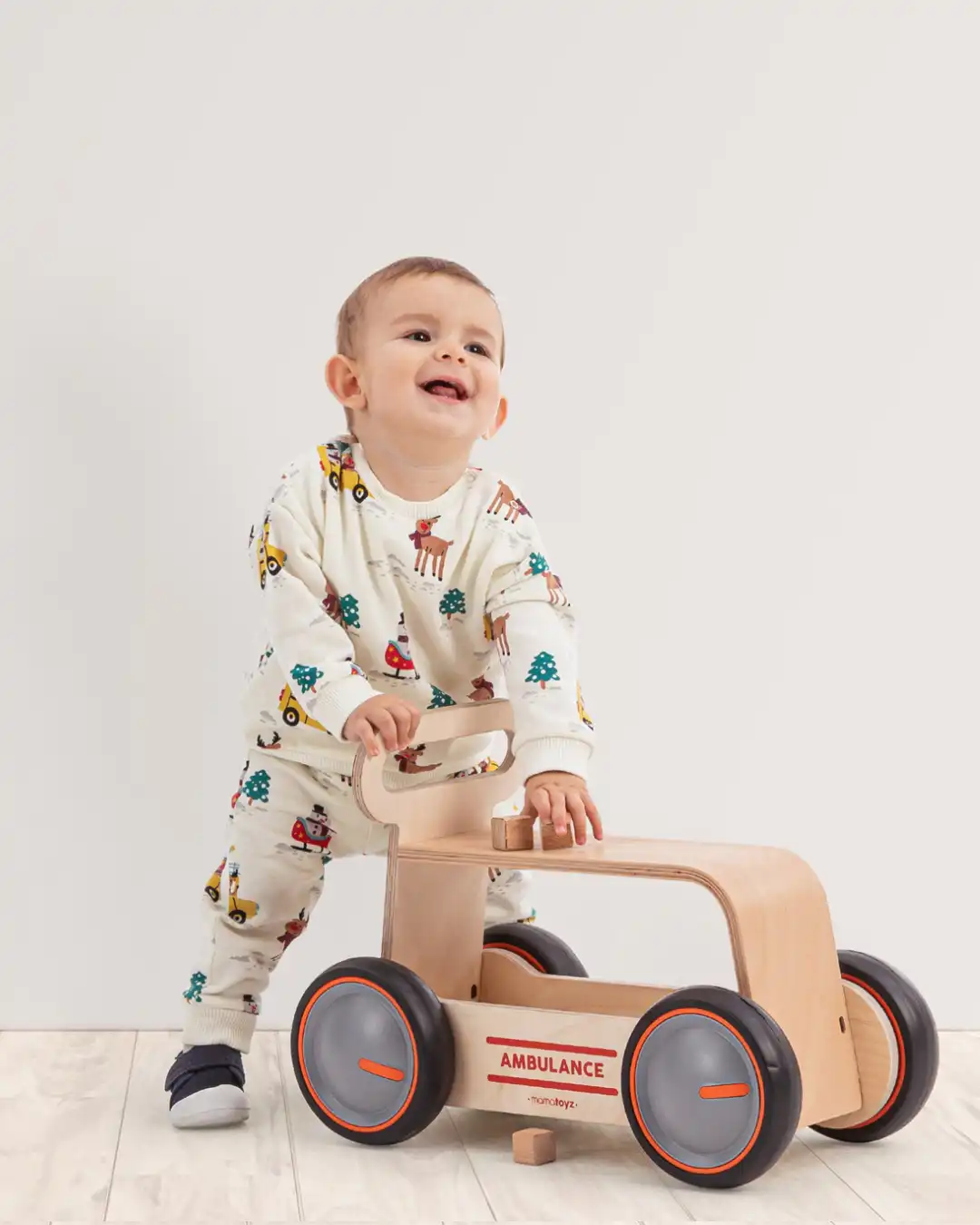 guralica za bebe sa sedistem od drveta i natpisom ambulance ispred decaka