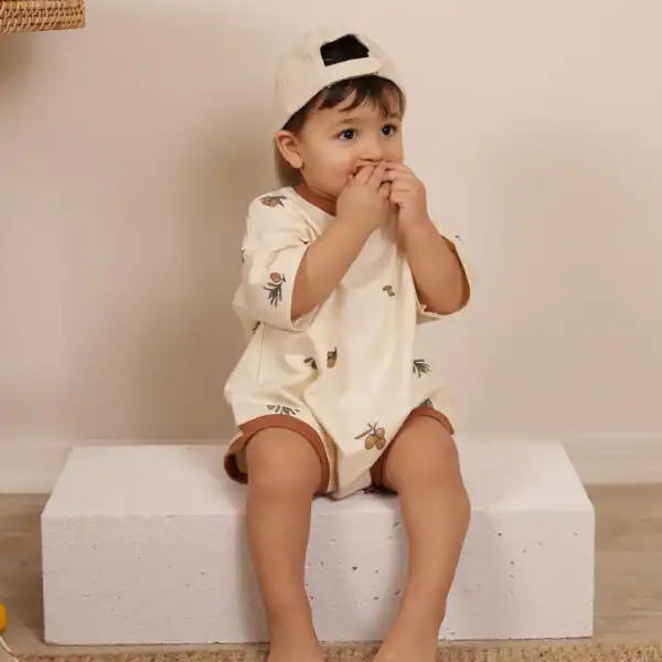 romper za bebe krem boje sa braon rubovima i motivom maslina na decaku
