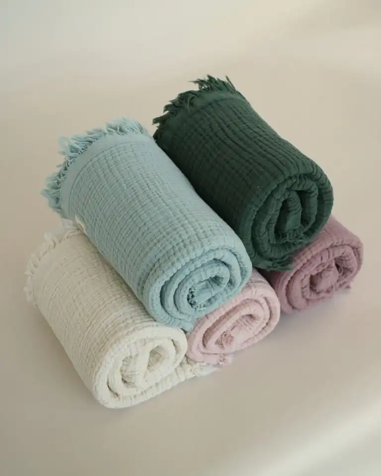 prekrivac od cetiri sloja muslina puderroze prljavoroze krem tamnozelene i mint boje urolani i slozeni jedan na drugi