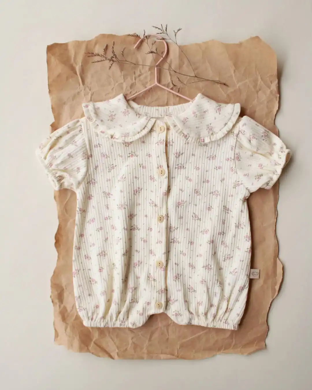 romper sa karnerima krem boje sa motivom rozih svetica na pozadini