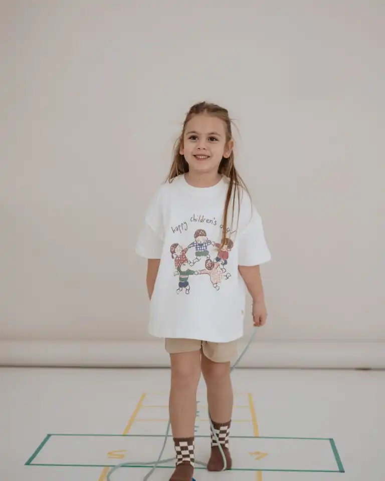 majica bele boje sa printom 5 dece koja se drze za ruke i vrte u krug sa natpisom happy children's day